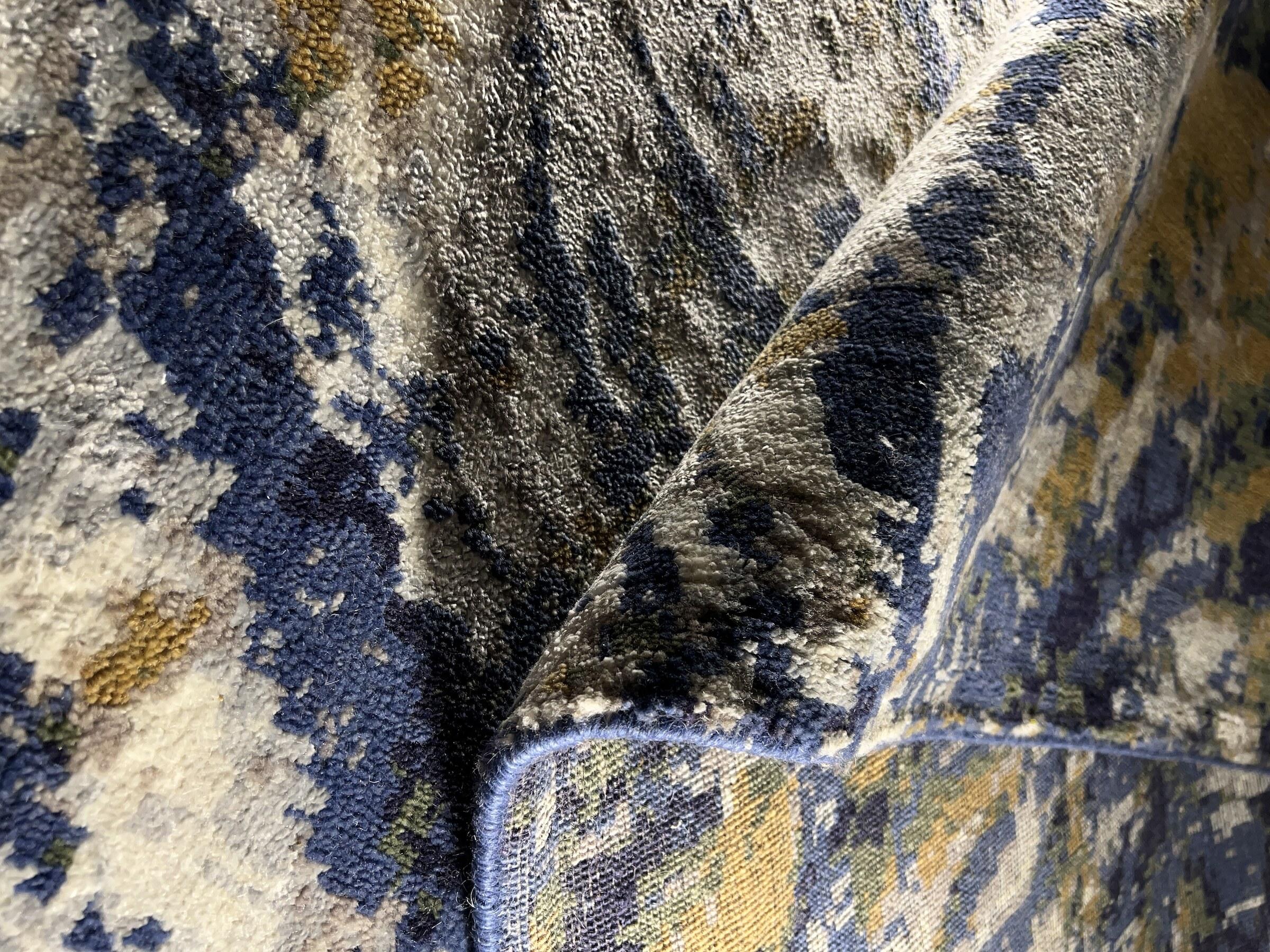 The folded edge of a hand-knotted Raheem & Son rug in blue and gold